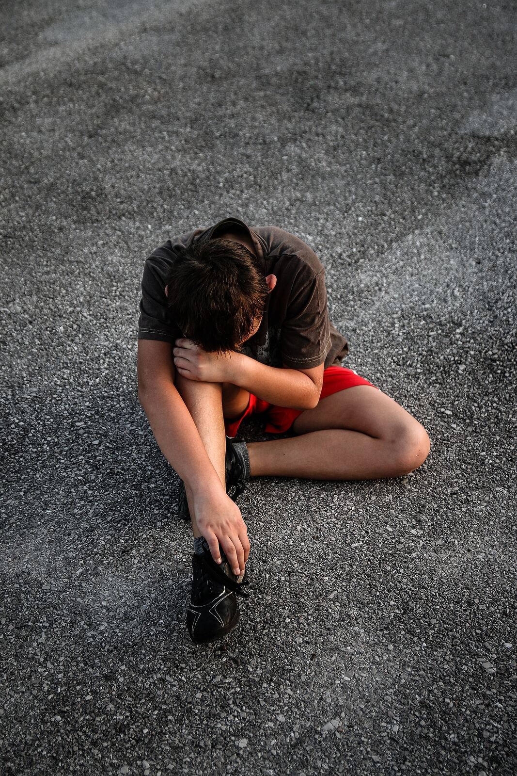 Young child sitting alone on ground looking distressed showing youth mental health challenges